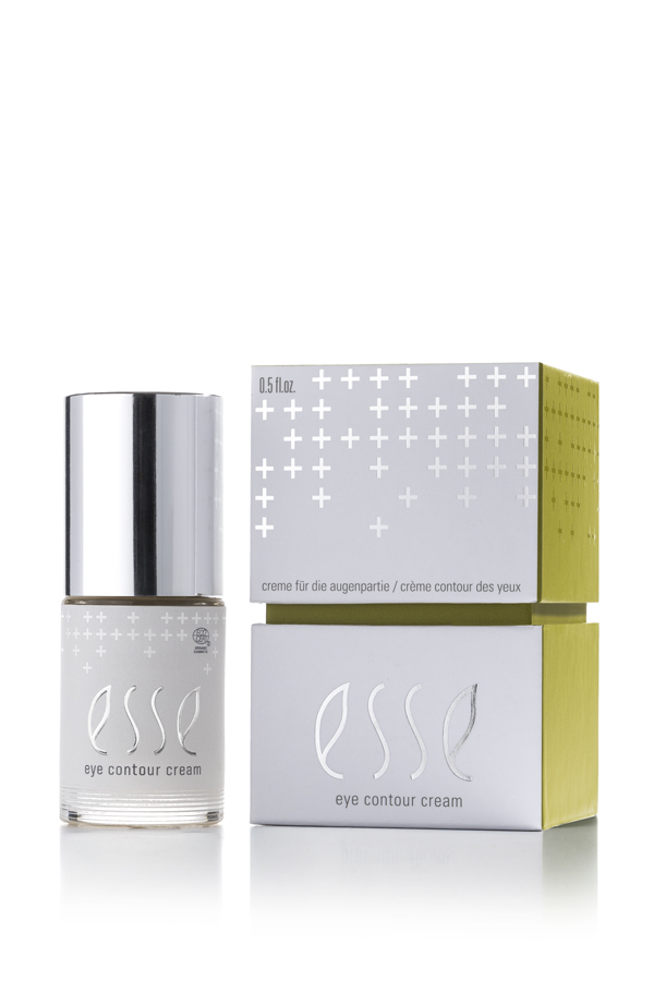 The Esse Eye Contour Cream bottle with a silver cap is shown beside its white and green box, which features minimalist text and plus sign patterns.