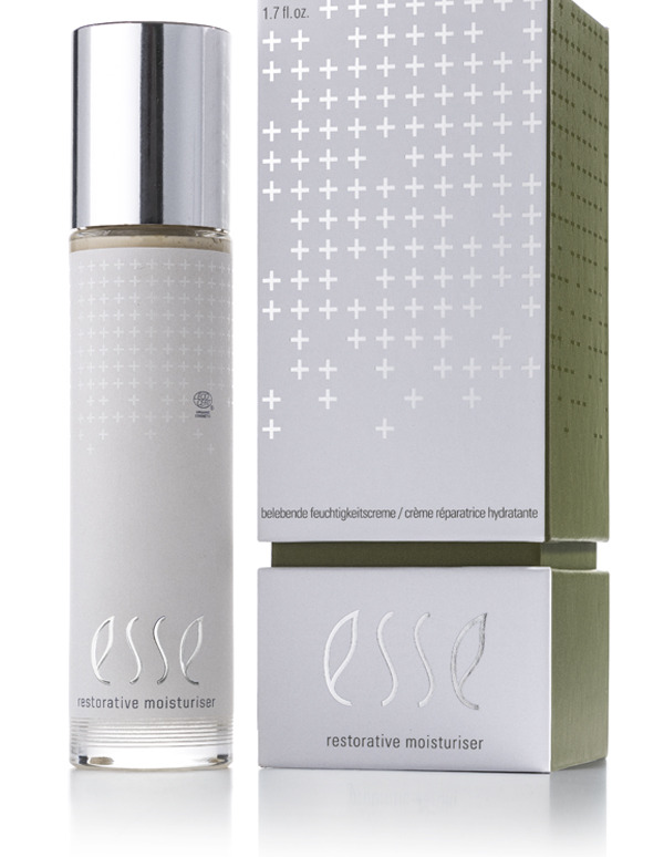 A bottle of Esse Restorative Moisturiser with a silver cap stands beside its matching box, both displaying a modern look with white crosses and minimalist text on silver and green backgrounds.