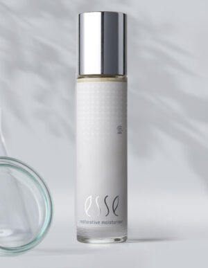 A sleek, cylindrical bottle of Esse Restorative Moisturiser with a silver cap and minimalist white label stands against a light gray background with subtle shadows.