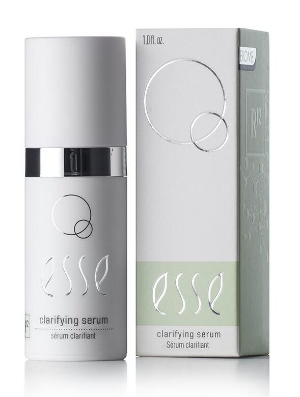 A 1.01 fl. oz. bottle of Esse Clarifying Serum is displayed alongside its packaging. The bottle, which is white with a silver cap, bears a label adorned with elegant circular designs. The packaging mirrors the design of the bottle and includes additional informational text.