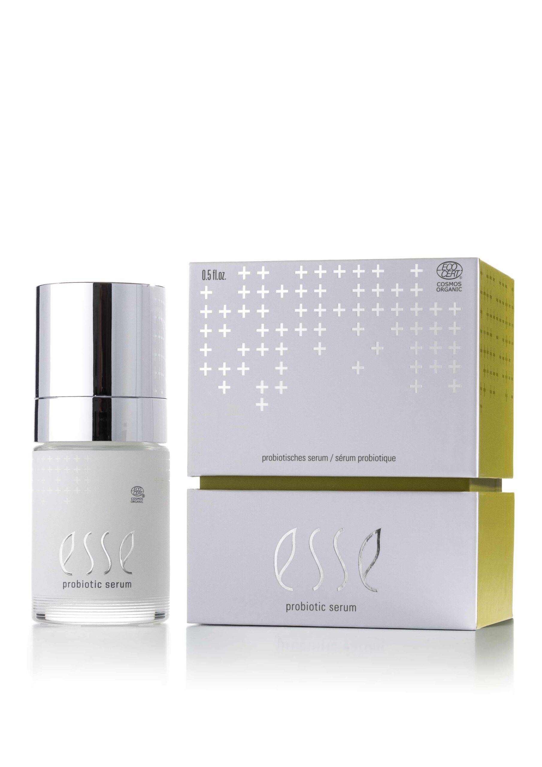 The Esse Probiotic Serum is displayed with a silver cap beside its matching white and yellow box, which features a minimalist design with plus sign patterns.